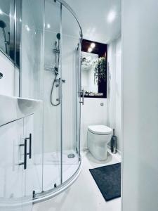 ein weißes Bad mit einer Dusche und einem WC in der Unterkunft Apt 03 Beachside Beauty Central Studio Steps from Cafes in Brighton & Hove