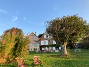 two chairs sitting in the grass in front of a house at Chambres d'hôtes Les 4 Vents Pointe du Hoc - Landing Beaches in Grandcamp-Maisy