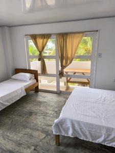 um quarto com 2 camas e uma grande janela em Hotel Palmetto Beach Coveñas em Coveñas