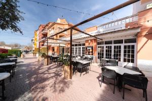 eine Terrasse mit Tischen und Stühlen und ein Gebäude in der Unterkunft Appartement Gran Reserva 9 - WeHostYou in Empuriabrava