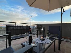 einen Tisch mit Gläsern und eine Flasche Wein auf dem Balkon in der Unterkunft Gardenie Home: delizioso villino vista mare in Messina