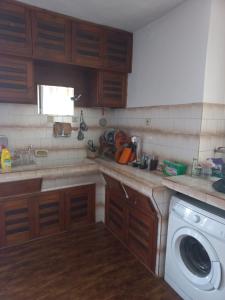uma cozinha com armários de madeira e uma máquina de lavar roupa em Къща в село Катунци em Sandanski