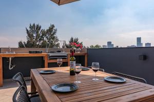 einen Holztisch mit Gläsern Wein auf der Terrasse in der Unterkunft Espectacular departamento con terraza en CDMX in Mexiko-Stadt