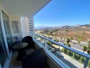 balcón con mesa, sillas y vistas a la ciudad en Hermoso y Moderno Loft en Dunas de Montemar Concòn, en Concón