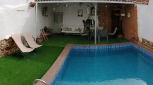 a swimming pool with green grass next to a house at Casa Rural Abuela Maxi in Ríolobos