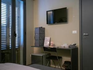 um quarto com uma secretária e uma televisão na parede em Dea's Rooms em Noto