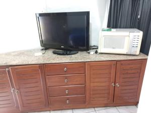 une télévision et un four micro-ondes sur un comptoir dans l'établissement Suíte Búzios, à Búzios