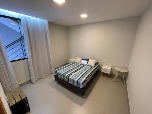a bedroom with a bed and a table and a window at Reserva Santa Helena in Anchieta