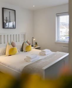 a white bedroom with a bed with yellow pillows at Hope Apartments Belfast - Tullymore in Belfast