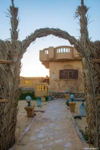 ein Torbogen vor einem Gebäude mit Pflanzen in der Unterkunft غزاله كامب in Siwa