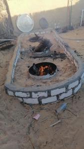a brick oven with a fire in the dirt at غزاله كامب in Siwa