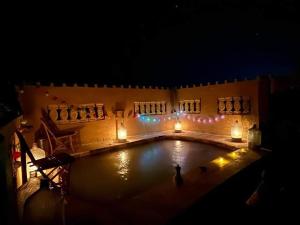 una piscina por la noche con velas y luces en غزاله كامب en Siwa