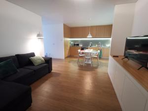 a living room with a black couch and a kitchen at Galé T3 in Caloura