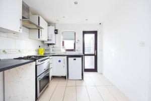 a kitchen with white appliances and a white tile floor at 4 Bedroom House 2 baths Dagenham in Dagenham