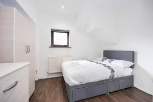 una camera da letto con un letto con lenzuola bianche e una finestra di 4 Bedroom House 2 baths Dagenham a Dagenham