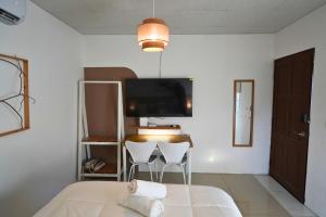 a bedroom with two white chairs and a tv at Casita Cumbrera en Penonomé in Penonomé