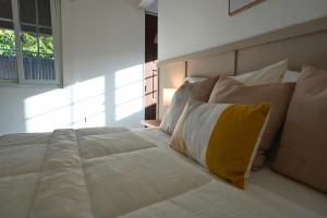 Una cama blanca grande con una almohada amarilla. en Casita Cumbrera en Penonomé, en Penonomé