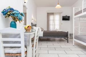 Un dormitorio con una cama y una mesa con un jarrón de flores en Depis studios & apartments, en Naxos Chora