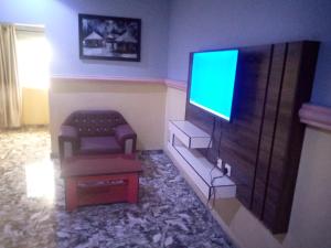 sala de estar con sofá y TV de pantalla plana en De Jacob's Hotel & Suites, en Umuinya
