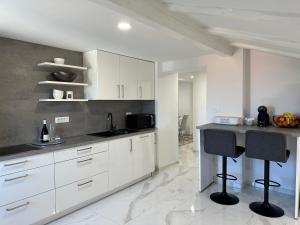 eine Küche mit weißen Schränken und einer schwarzen Arbeitsplatte in der Unterkunft Apartma 78 in Koper