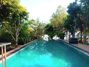 a swimming pool with blue water and trees at Jayaa Villas Bolgoda - Full Villa in Panadura
