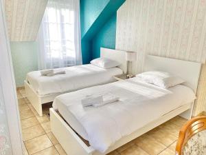 two beds in a room with blue walls at Villa Briconico in Gonesse