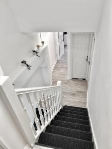 un escalier avec des murs blancs et des escaliers noirs dans l'établissement Westfield London Shepherds Bush, à Londres