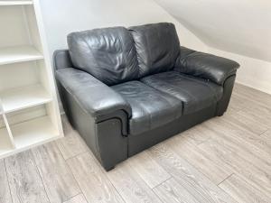 - un canapé en cuir noir dans une pièce dans l'établissement Westfield London Shepherds Bush, à Londres