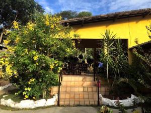 ein gelbes Haus mit einem Garten mit gelben Blumen in der Unterkunft Zil Hospeda in Pipa