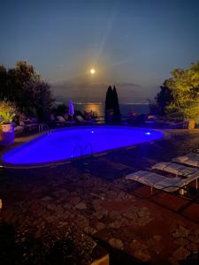 a large blue swimming pool in a yard at night at Maison Du Reve Scario in Scario