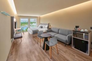 a living room with a couch and a bed and a table at City Express Plus by Marriott San Luis Potosi in San Luis Potosí