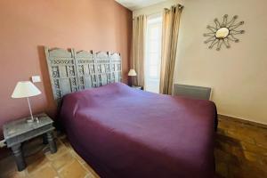 ein Schlafzimmer mit einem großen lila Bett und einem Fenster in der Unterkunft Le Chef d'Escadron in Bonnieux