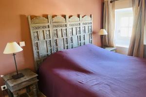 a bedroom with a bed with a purple bedspread at Le Capitaine in Bonnieux