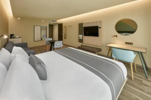une chambre d'hôtel avec un grand lit et un salon dans l'établissement City Express Plus by Marriott San Luis Potosi, à San Luis Potosí