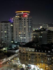 een hoog gebouw met 's nachts een klok erop bij Sky Hotel Tirana in Tirana