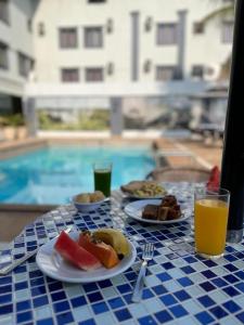 a table with plates of food and a glass of orange juice at Hotel Fenice in Foz do Iguaçu
