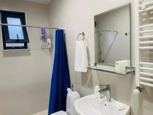 a bathroom with a sink and a blue shower curtain at maria house _2 in Kutaisi