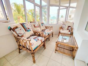 a room with chairs and a table and windows at Fibonacci Beachfront Apartment in Flic-en-Flac