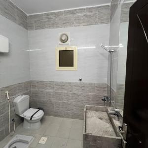 a bathroom with a toilet and a tv on the wall at شقق سنتارا الفندقية in Taif