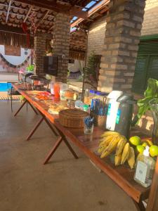 a long wooden table with a bunch of bananas on it at Pousada Flor De Jambú in São Miguel do Gostoso
