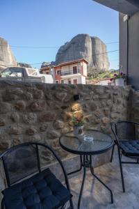 a table and chairs on a patio with a stone wall at Akratos House in Kastraki