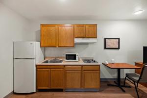 a kitchen with wooden cabinets and a white refrigerator at WoodSpring Suites El Paso in El Paso