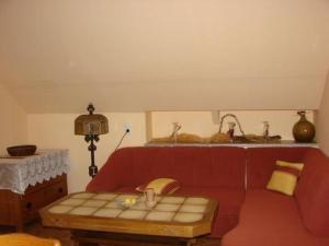 - un salon avec un canapé rouge et une table dans l'établissement Appartement in Schelingen mit Garten und Grill, à Schelingen