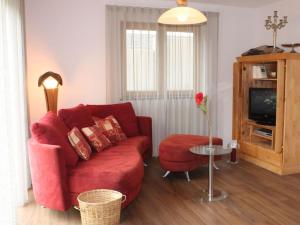 a living room with a red couch and a tv at Alpchalet Staufner Quelle in Oberstaufen