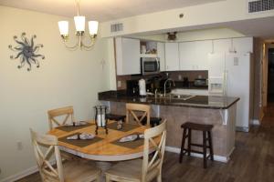 a kitchen with a dining table and a kitchen with a spider on the wall at Four Winds 402 by ALBVR - Amazing beachfront condo with private balcony & unbelievable views! in Orange Beach
