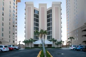 a building with a palm tree in a parking lot at Four Winds 402 by ALBVR - Amazing beachfront condo with private balcony & unbelievable views! in Orange Beach