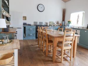 a kitchen with blue cabinets and a wooden table and chairs at Burrows in Venn Ottery