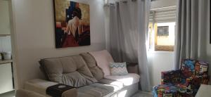 uma sala de estar com um sofá e uma cadeira em Ap 1 quarto Mobiliado em Gravataí
