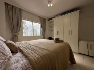 een slaapkamer met een groot bed en een raam bij BC01- Suíte+1 | Centro | Churrasqueira | Garagem in Balneário Camboriú