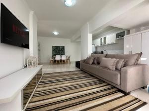 een woonkamer met een bank en een flatscreen-tv bij BC01- Suíte+1 | Centro | Churrasqueira | Garagem in Balneário Camboriú